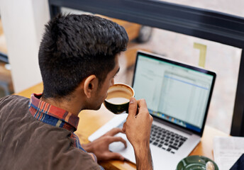 Man drinking coffee while working with a laptop in a cafeteria doing research for remote work project. Technology, caffeine and male employee planning a creative report on a computer in restaurant.