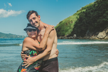 Fototapeta na wymiar Mãe e filho abraçados na praia