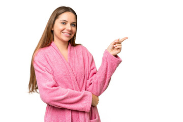 Young woman in a bathrobe over isolated chroma key background pointing finger to the side