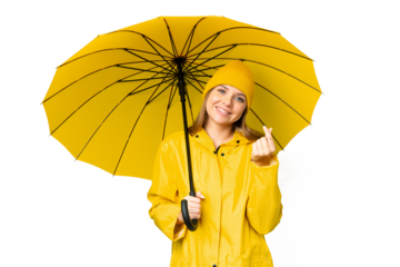 Young blonde woman with rainproof coat and umbrella over isolated chroma key background making money gesture