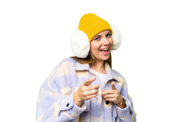 Young blonde woman wearing winter muffs over isolated chroma key background pointing to the front...