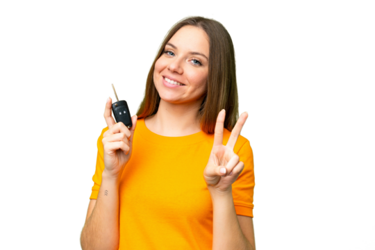 Young woman holding car keys over isolated chroma key background smiling and showing victory sign