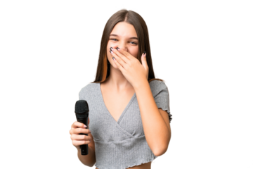 Teenager singer girl picking up a microphone over isolated background happy and smiling covering mouth with hand
