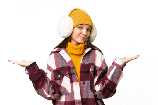 Teenager caucasian girl wearing winter muffs over isolated background having doubts while raising hands