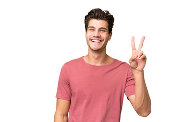 Naklejka premium Young handsome caucasian man over isolated background smiling and showing victory sign