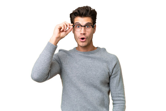 Young handsome caucasian man over isolated background with glasses and surprised