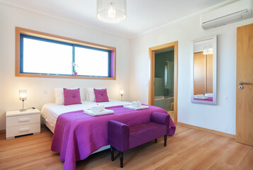 Modern bedroom with a large double bed in pink tones with towels. bathroom for customers.