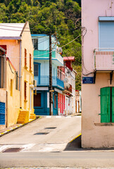 Colorful facades of houses on the waterfront of Saint Pierre on tropical island Martinique (France, Lesser Antilles). Idyllic atmosphere with narrow one way streets on a sunny day in tourist village. - obrazy, fototapety, plakaty