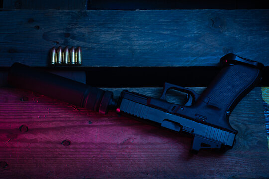 Photo with weak color illumination as an artistic technique.  Pistol with silencer and ammo.