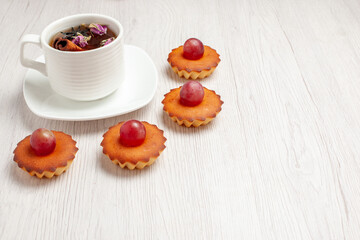 front view yummy little cakes with cup of tea on white background fruit tea dessert cookie biscuit cake pie