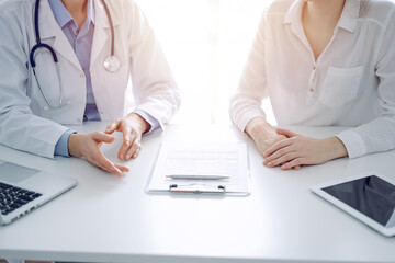 Fototapeta premium Stethoscope lying on the tablet computer in front of a doctor and patient sitting opposite each other at the background . Medicine, healthcare concept