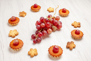 front view yummy little cakes with grapes and cookies on white background fruit tea dessert cookie biscuit cake pie