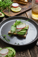 White bread toasts with cream cheese, avocado, cucumber and radish in a plate