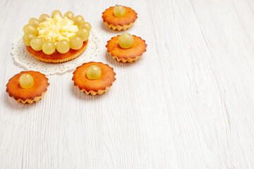 front view yummy little cakes with green grapes on a white background fruit tea dessert cookie biscuit cake pie