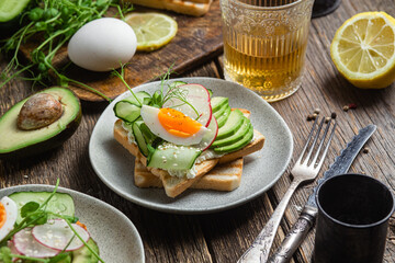White bread toasts with cream cheese, egg, avocado, cucumber and radish in a plate