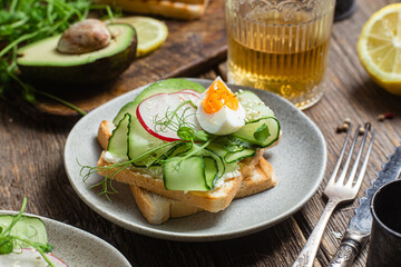 White bread toasts with cream cheese, egg, avocado, cucumber and radish in a plate