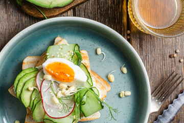 White bread toasts with cream cheese, egg, avocado, cucumber and radish in a plate