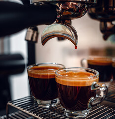 Professional espresso machine while preparing two espressos shot in a coffee shop. Close-up of espresso pouring from the coffee machine