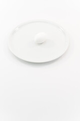 immagine di piatto in ceramica  bianco con uovo di gallina bianco su superficie bianca