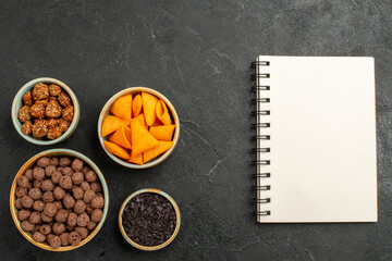 top view chocolate flakes with chips notepad and nuts on dark background corn color nut