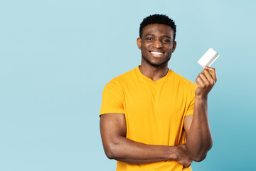 Portrait of young handsome African American businessman holding credit card looking at camera...