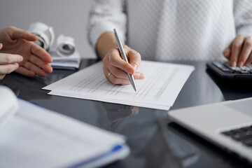 Woman accountant using a calculator and laptop computer while counting taxes for a client. Business audit and finance concepts