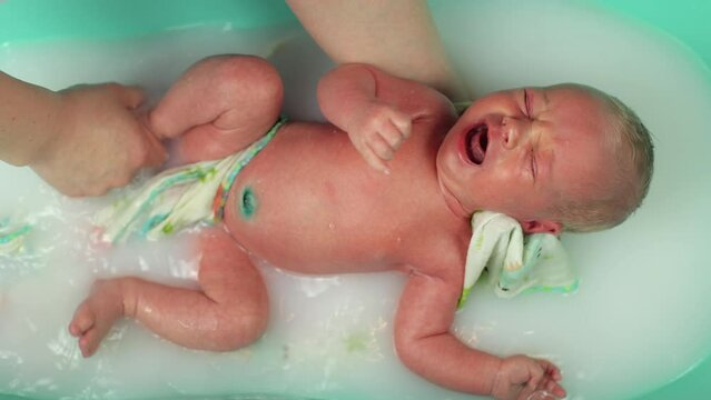 A newborn baby. Newborn baby boy swimming in water. The first days of a two-week-old baby's life. A child with white hair. Joy for parents, a newborn boy. Children's procedures. Small bathroom