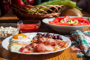 Fried eggs, bacon and beans on a wooden table...vegetable for the breakfast...