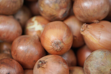Obraz premium Yellow sweet onions pile in grocery market. Golden pile of beautiful bulb onions.