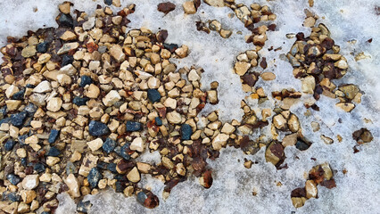 Rocks and stones laying on the ground with icy snow on a cold winter day. Abstract Background, texture and frame for place for text and copy space