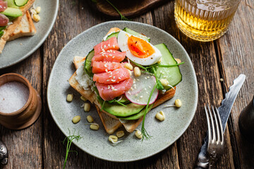toasts with cream cheese, salmon, egg, avocado, cucumber  in a plate
