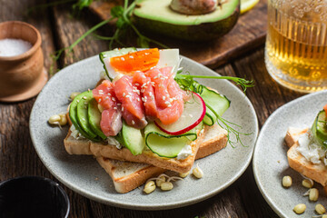 toasts with cream cheese, salmon, egg, avocado, cucumber  in a plate