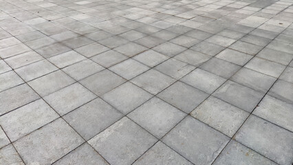 Gray tiles on the sidewalk in the city outdoors. Background and texture with lines and squares of...