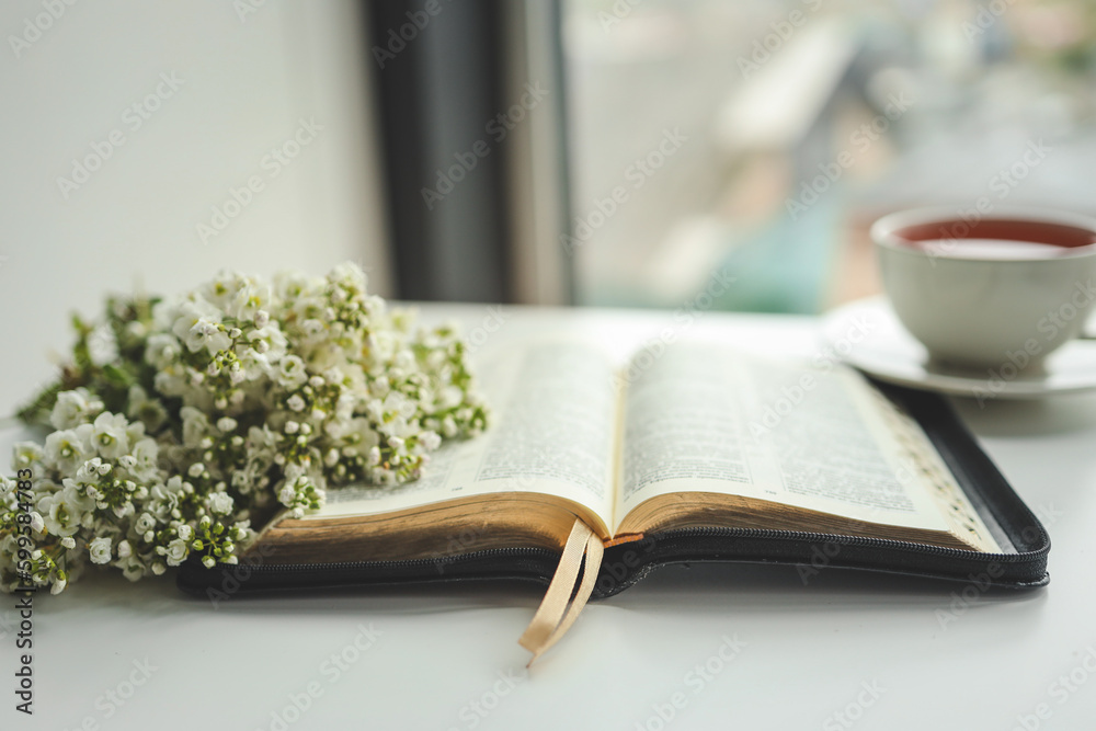 Wall mural open bible with flowers and a cup of tea on a white background