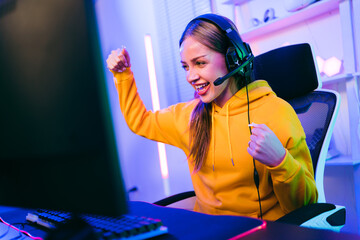 Portrait of a Caucasian female gamer celebrating victory in front of the gaming table. Gamer winning an esports game with victory emotion. The player rejoices in victory in the competition.
