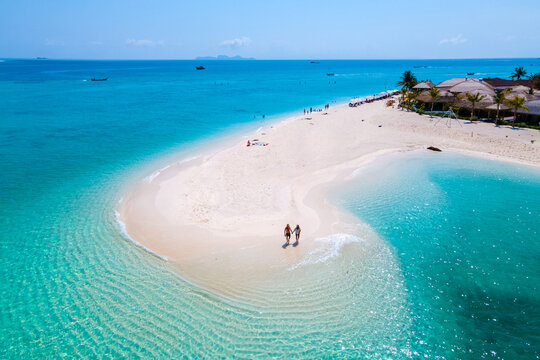 men and women walking on a sandbar in the ocean of Koh lipe Southern Thailand during vacation