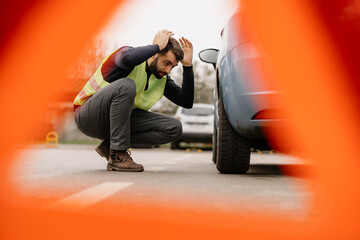 A Man is standing next to his car formally dressed and looking worried about the cars engine problem.