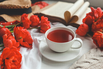 Beautiful spring composition, good morning concept. Cup of tea, peonies, open old book