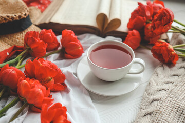 Beautiful spring composition, good morning concept. Cup of tea, peonies, open old book