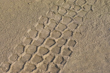 Tracks of four-wheel-drive tires on the sand by the river.
