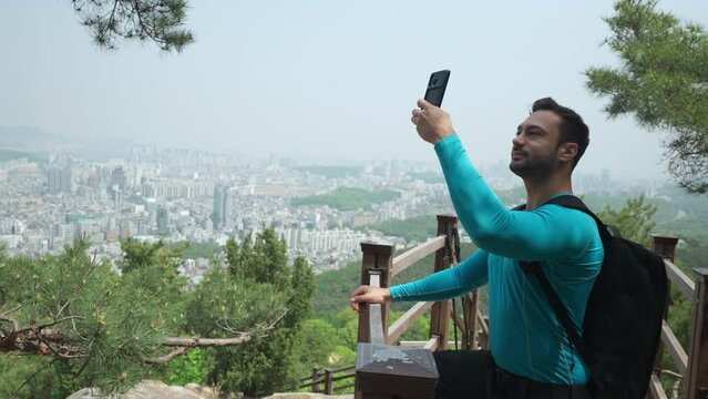 Hiker Man Takes Selfie Photos on a Mountain Hiking Trail With a Seoul City Overlook on Hazy Day