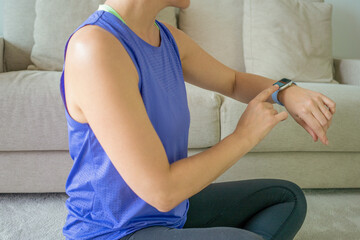 Close-up of caucasian woman checking pulse on her watch while training at her cozy flat. Sports, strength and endurance concept