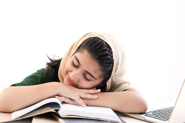 Adorable Muslim sleepy girl student wearing traditional hijab taking a nap, feeling bored, tired during studying and doing homework on table, kid reading book on white background, child education.