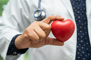 Doctor holding a red heart in hospital ward, healthy strong medical concept.