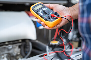 Asian auto mechanic check for repair under the hood of broken down car on the side of the road.
