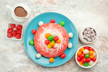 top view delicious pink cake with colorful candies on a white background color dessert cake rainbow candy