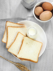 Fototapeta na wymiar Sliced Toast Loaf White Bread (Shokupan or Roti Tawar) for Breakfast on Wooden Background, Served with Egg and Milk. Breakfast Concept Picture