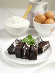 Brownies Kukus or Chocolate Steam Cake Brownies with marble chocolate glaze on top. Served in white ceramics pllate. Selective focus, white background
