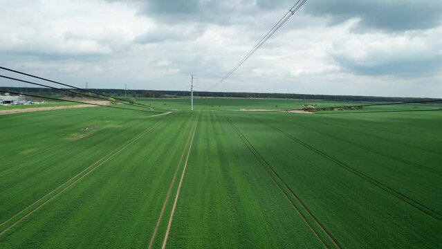 View from above of high-tension power line and ceramic insulators with city skyline and industrial zone.