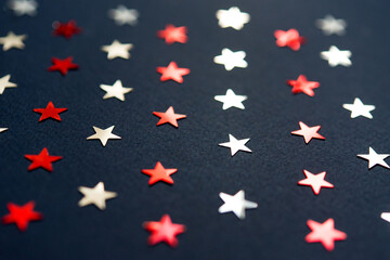 Blue abstract holiday background or texture with silver and red stars confetti on blue background. Copy space. Good backdrop for Christmas and New Year cards.